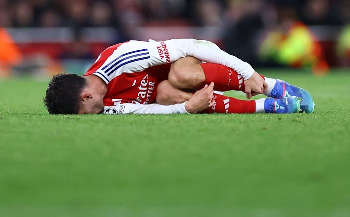 En Arsenal-spiller ligger på gresset og holder rundt beinet etter en skade